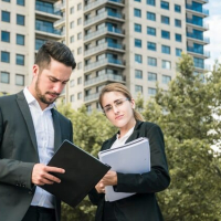 close-up-businessman-businesswoman-holding-documents-standing-front-building_23-2148026616